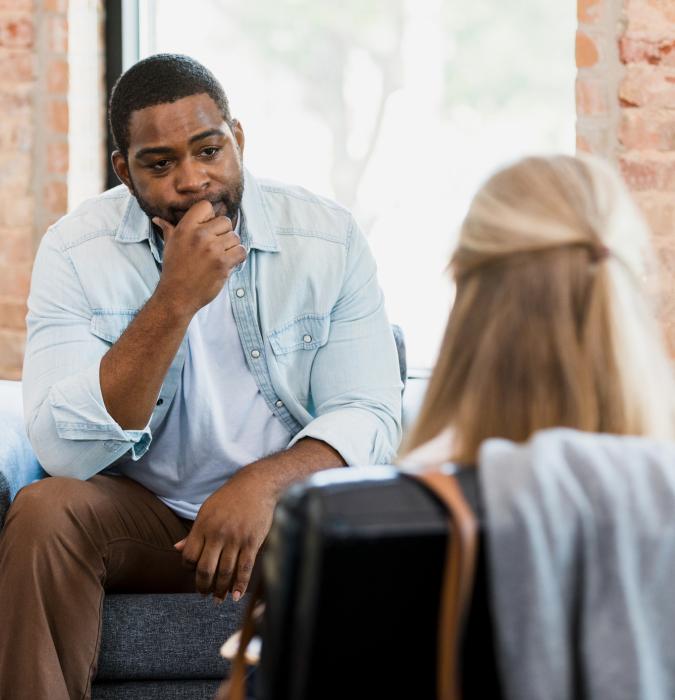 Exhausted mid adult man listens to female therapist 